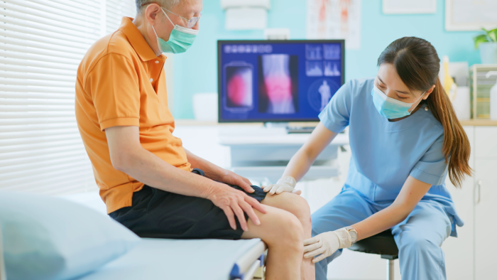 Licensed healthcare professional assessing the knee of a male patient.
