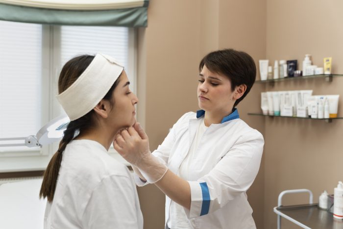 Healthcare professional carefully analyzing a female patient's face before Radiesse treatment.