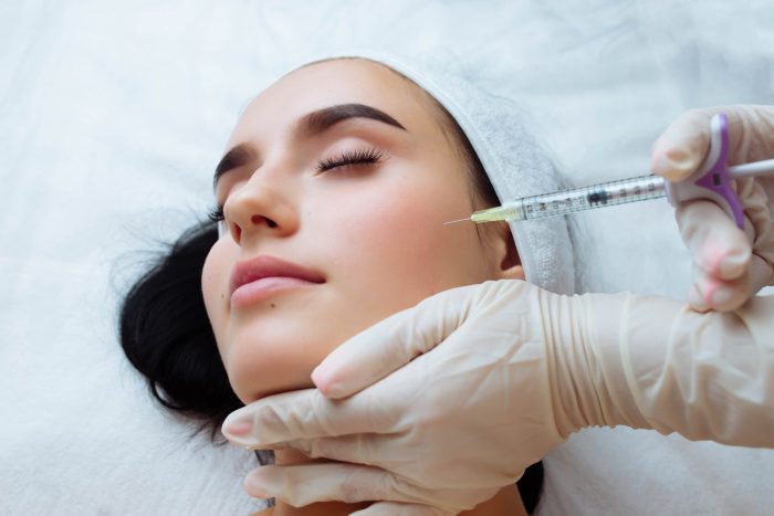 An aesthetic specialist performs Restylane procedure on a female patient.