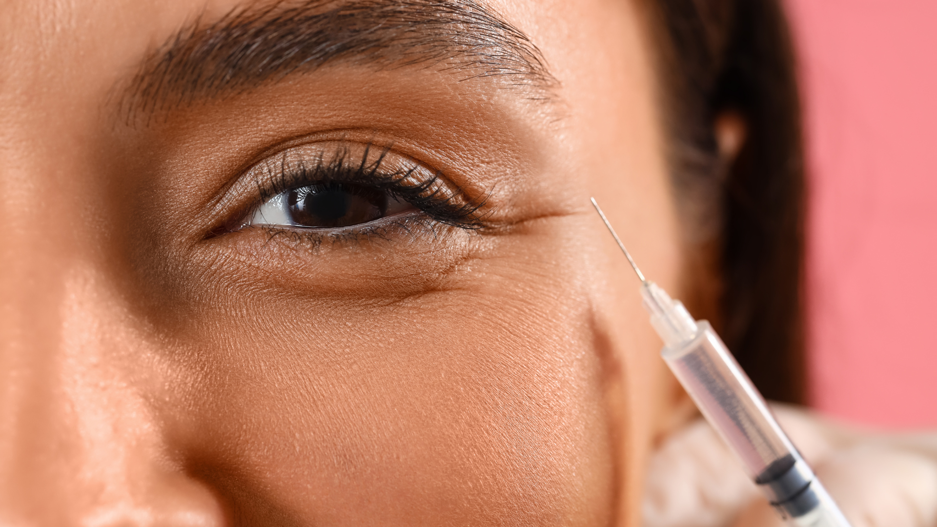 An excited woman receives under eye injection for facial rejuvenation.