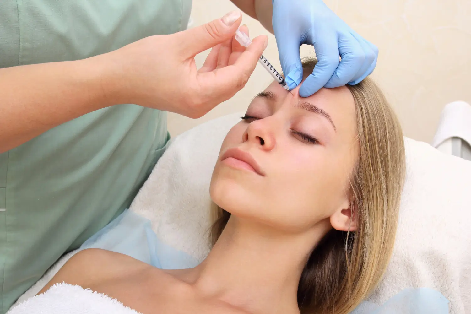 A beautiful young woman gets an injection in her forehead. A great representation of cosmetic and anti-aging treatments like Dysport or Botox.